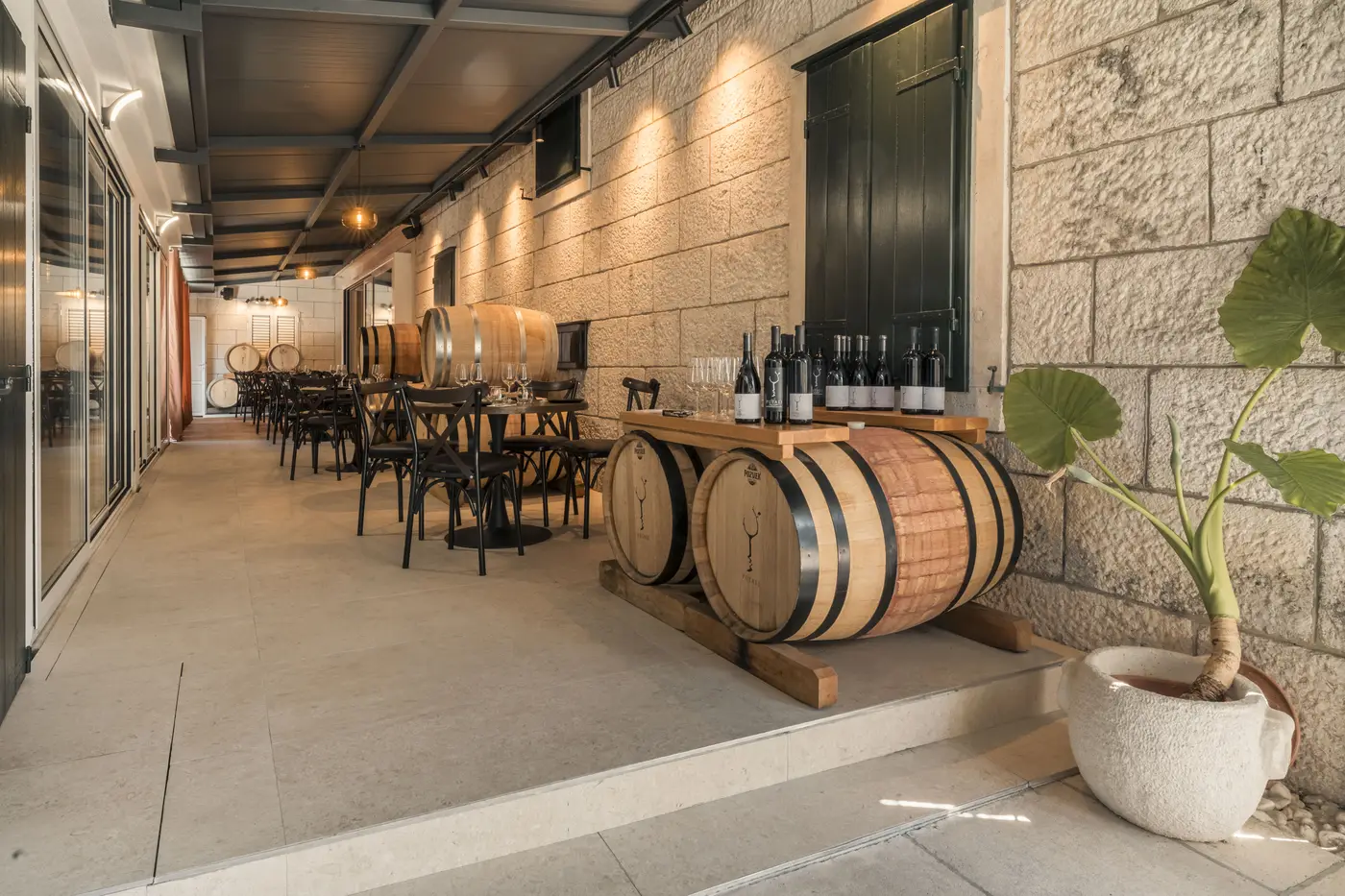 Stone-walled tasting terrace lined with oak barrels at Winery Kovač